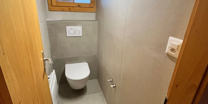Optimisation d'espace et pose de faïence murale. Rénovation de sanitaires avec WC suspendu et carrelage gris anthracite à Nendaz.