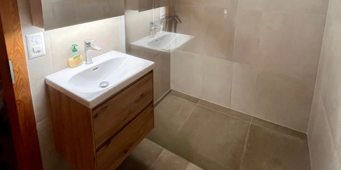 Pose de carrelage mural beige et installation de mobilier de salle de bain à Haute-Nendaz.